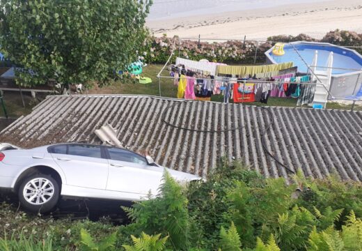 Saída de vía cun coche caído sobre o alpendre dunha vivenda na rúa Hermo, no concello de Miño